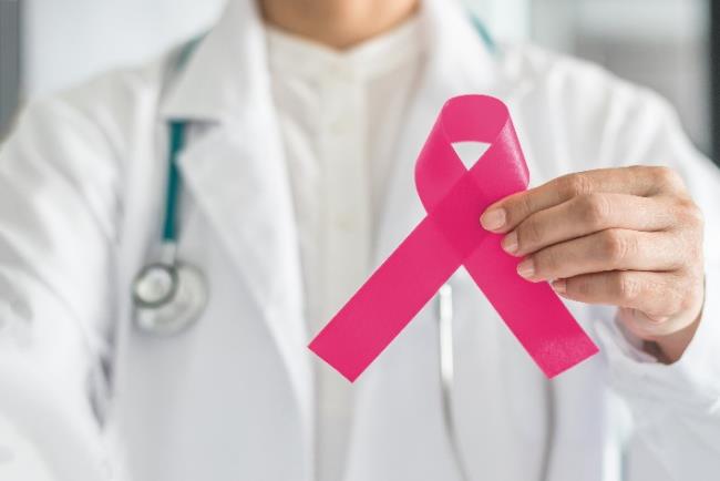 רופאה מחזיקה סרט ורוד המסמל העלאת מודעות לסרטן השד